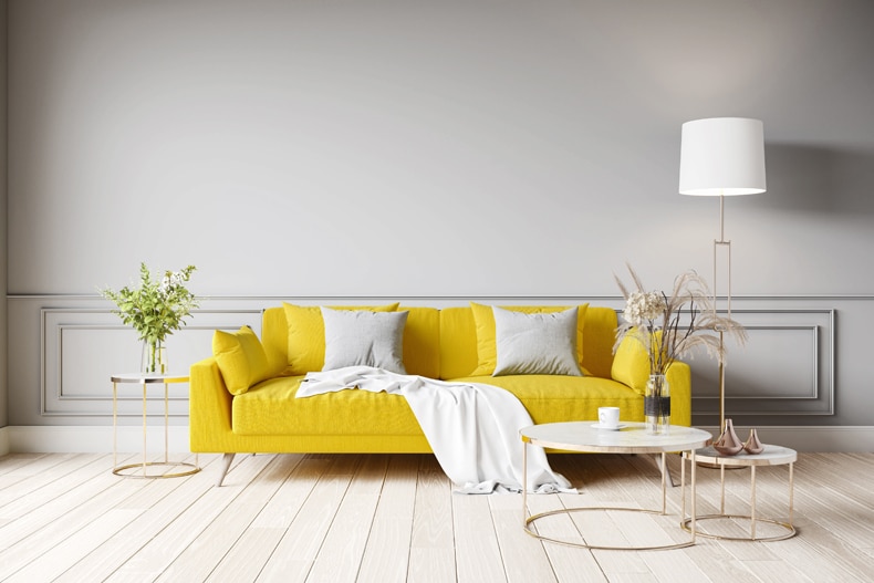 mustard sofa with a white thrown over blanket