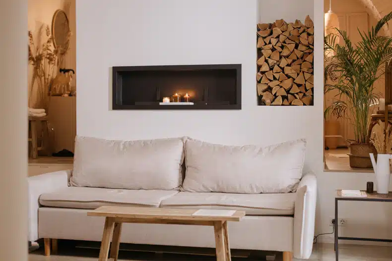 a minimalist scandinavian living room representing a minimalist fireplace, a beige couch, and a wooden coffee table