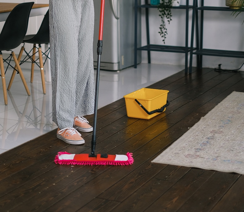 woman cleaning a hardwood floor with natural products