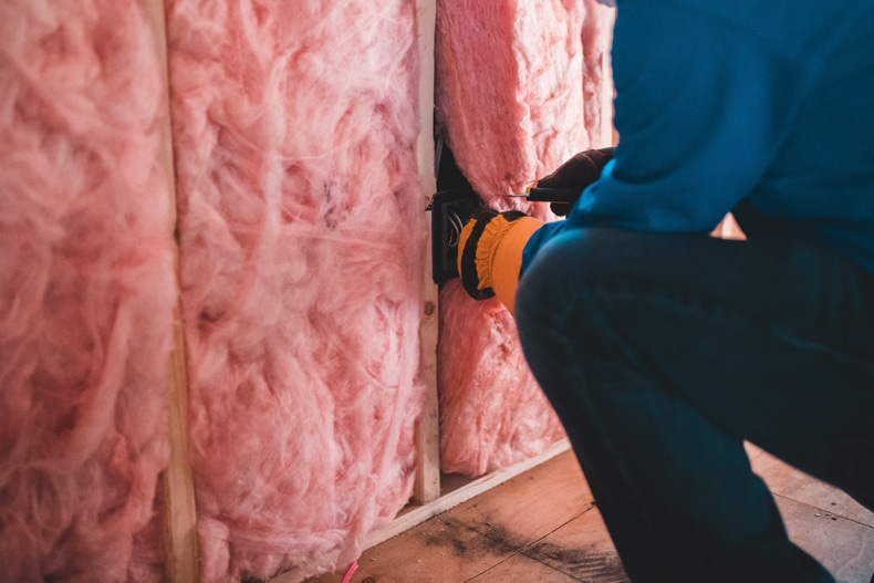 man installing fiberglass insulation for acoustic insulation