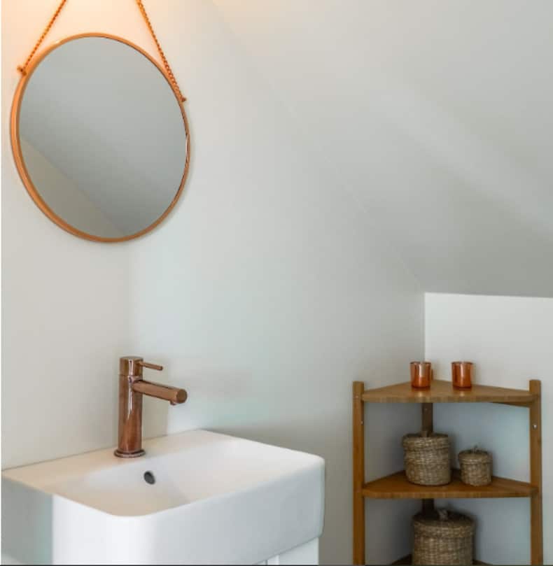a small bathroom with shelves, corner cabinets, hooks, and a rolling cart for maximizing storage space
