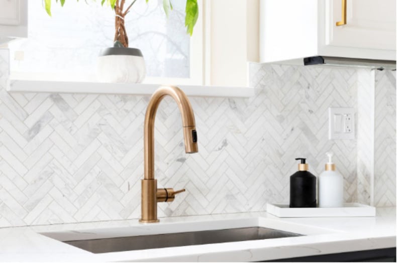 a glossy herringbone tiles installed on a kitchen backsplash, creating a stunning pattern and adding visual interest to the space