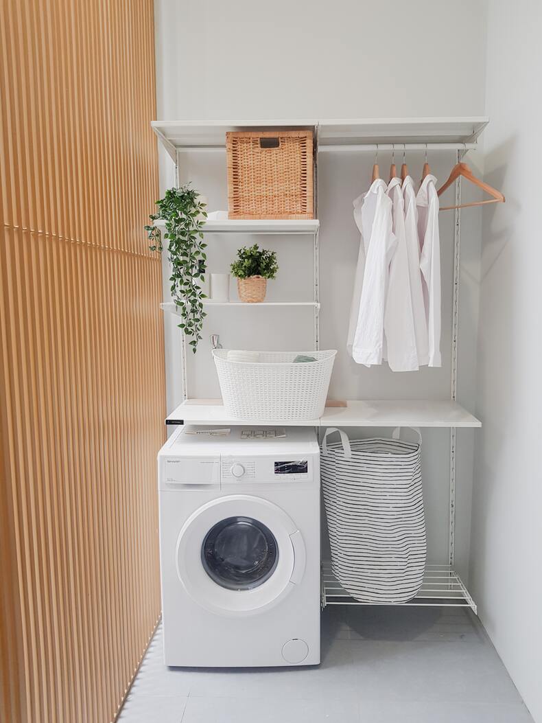 A compact laundry room with a stackable washer and dryer unit, a sink, and storage cabinets neatly arranged, making efficient use of limited space