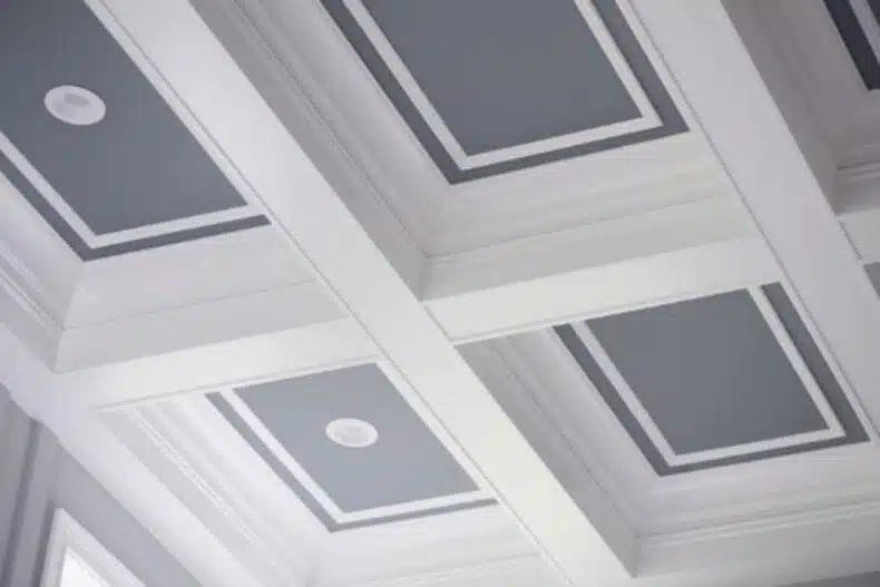 A coffered ceiling with golden painted patterns creates an opulent and majestic look in a room
