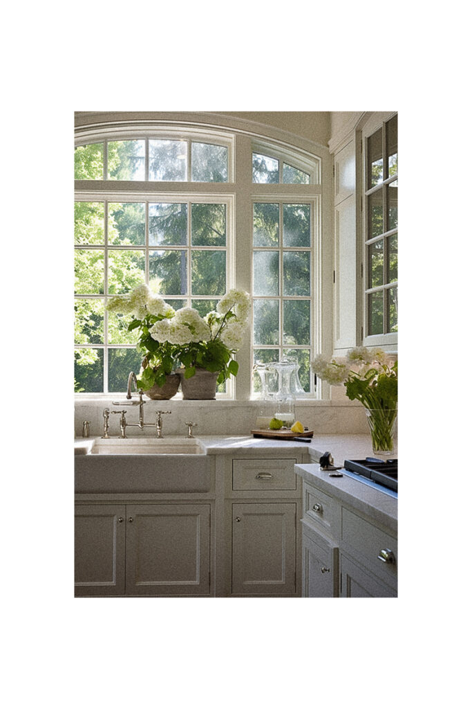 A kitchen with white cabinets and a window over the sink.