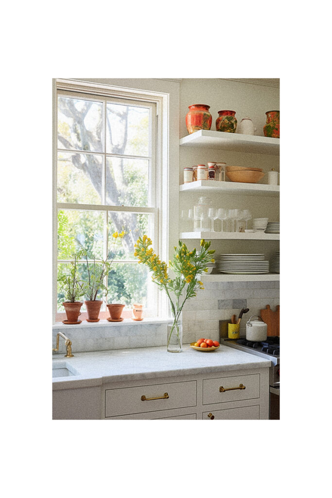 A white kitchen with shelves and a window over the sink.