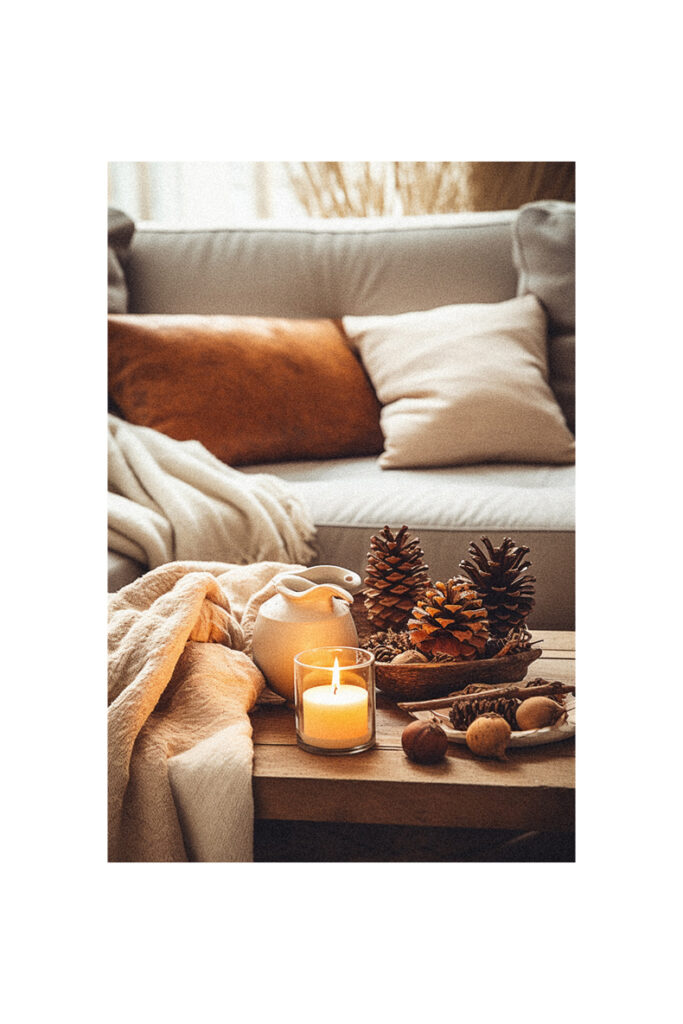 Fall decor for the home featuring a coffee table adorned with candles, pine cones, and a blanket.