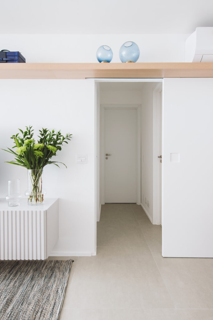 A white living room with a vase on top of a shelf.