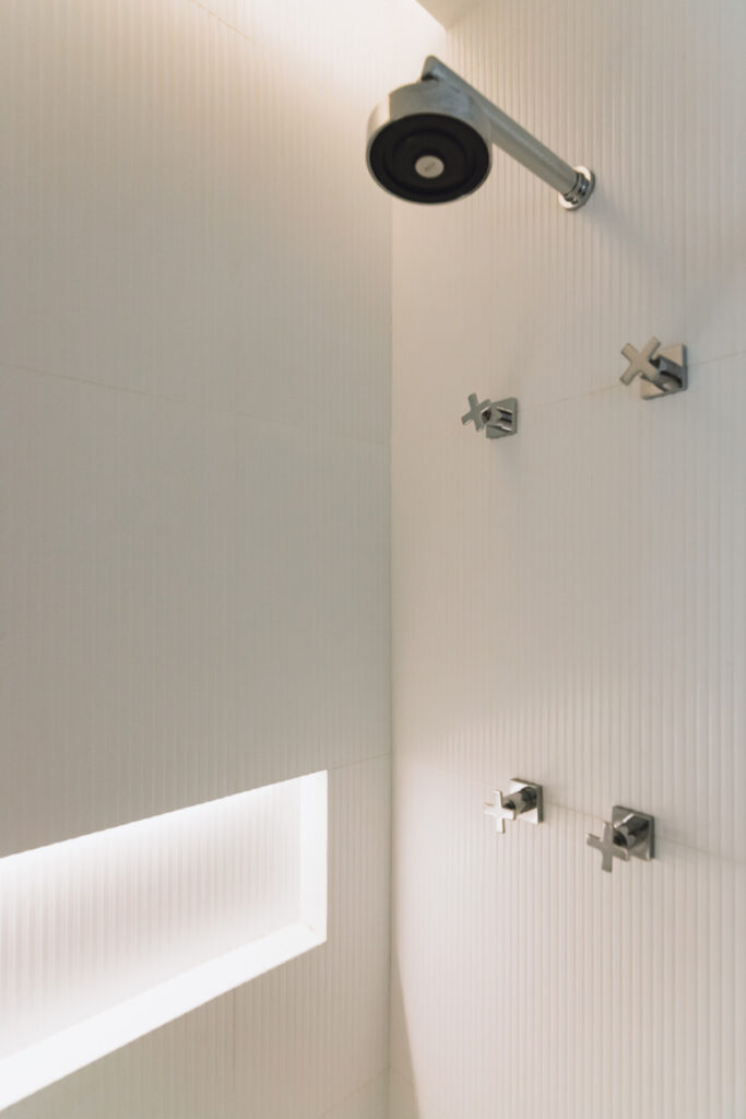 A white bathroom with a shower head and light fixtures.