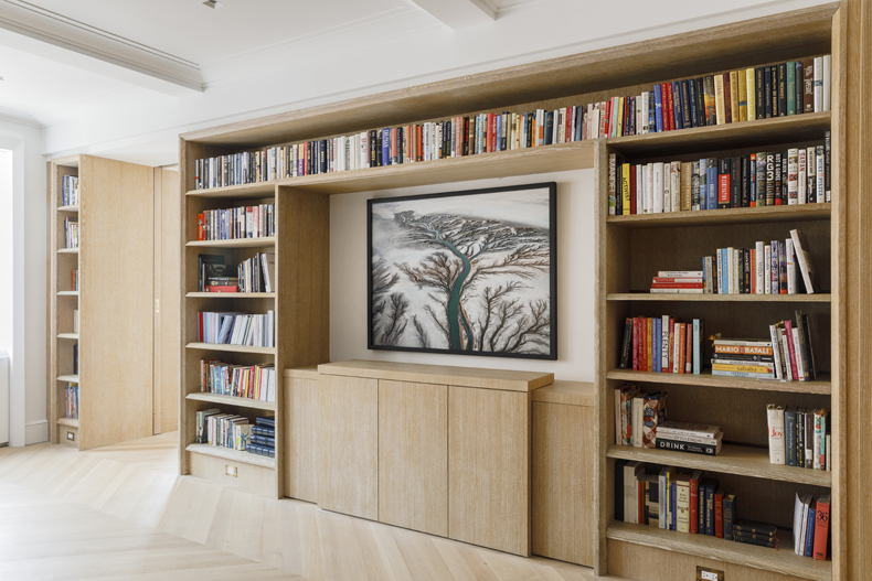 A living room with bookshelves and a painting.