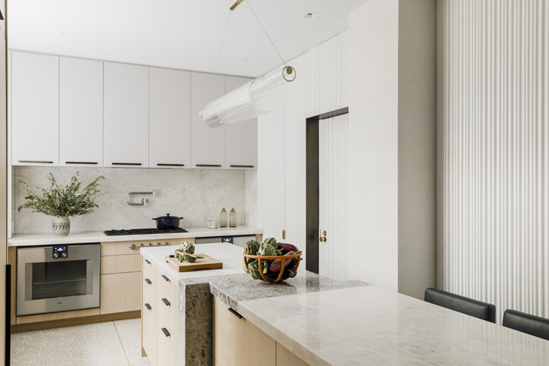 A modern kitchen with white cabinets and marble counter tops.