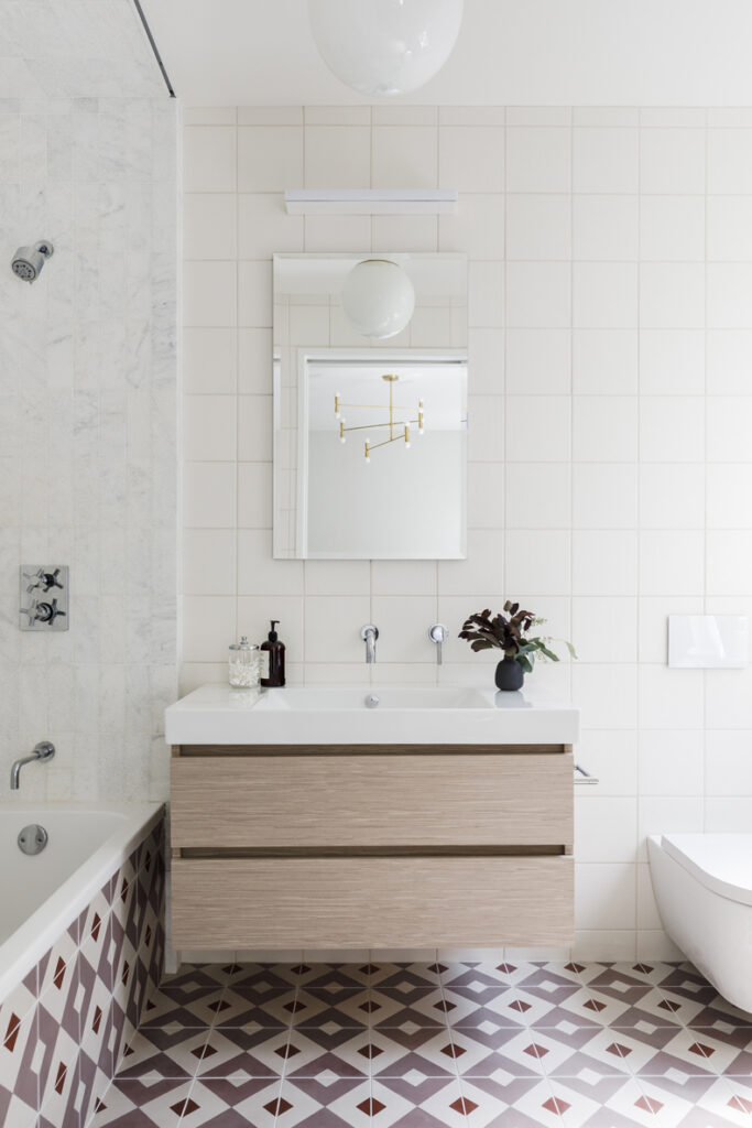 A white bathroom with a brown and white tiled floor.