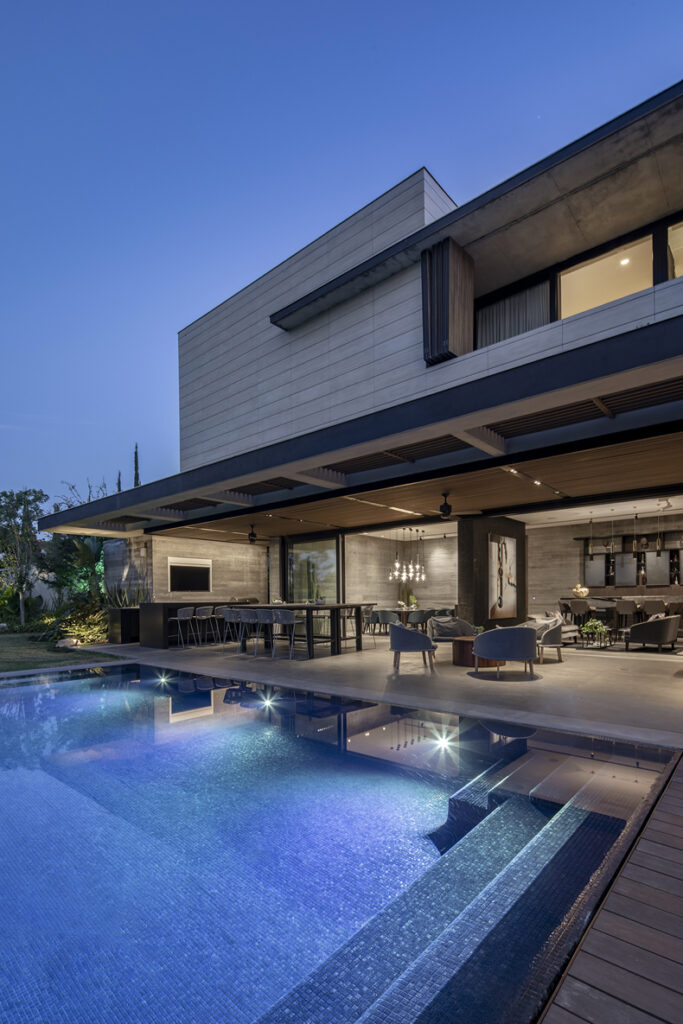 A modern house with a swimming pool at dusk.