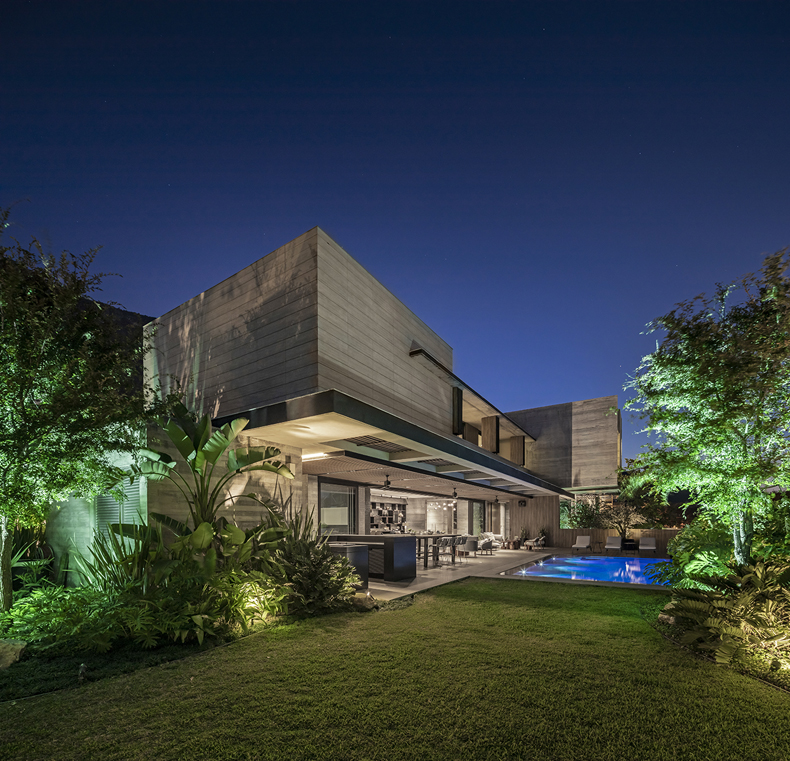 A modern house with a swimming pool at night.