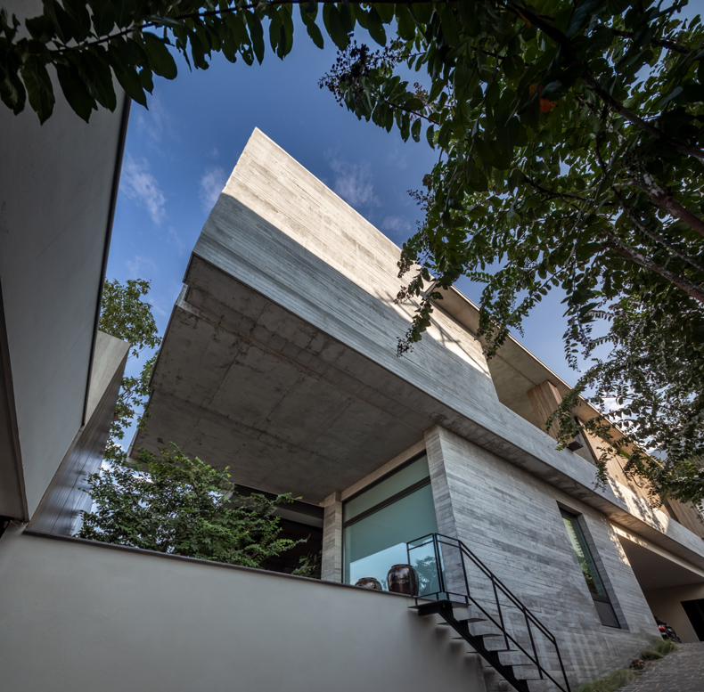 A modern concrete house with stairs and trees.