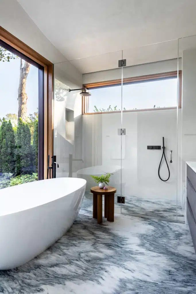 A modern bathroom with a marble tub and glass shower.