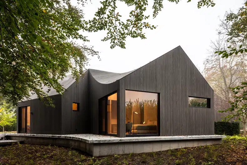 A modern black house in the woods.