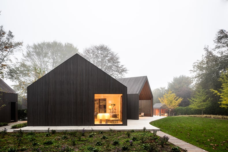 A black house in the middle of a grassy field.