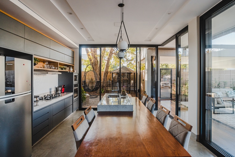 A modern kitchen with glass doors and a wooden table.