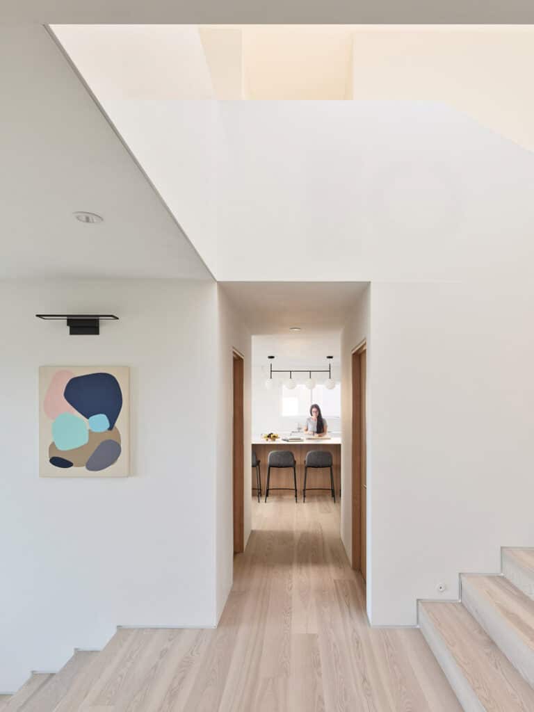 A white house with wooden stairs and a painting on the wall, fashioned by BLA Design Group.
