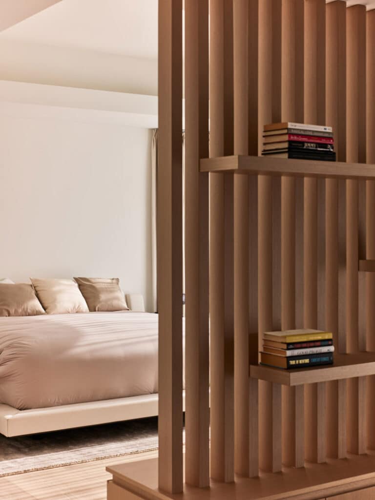 A bedroom fashioned by BLA Design Group with a bed and bookshelves.