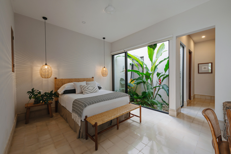 A bedroom with a bed and a plant in the room.