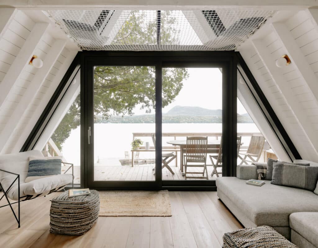 A lakeside chalet designed by Matiere Premiere Architecture with a large window in the living room.