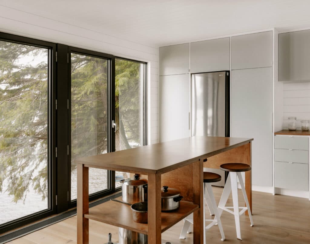 A chalet kitchen with stools and a view of a lake.