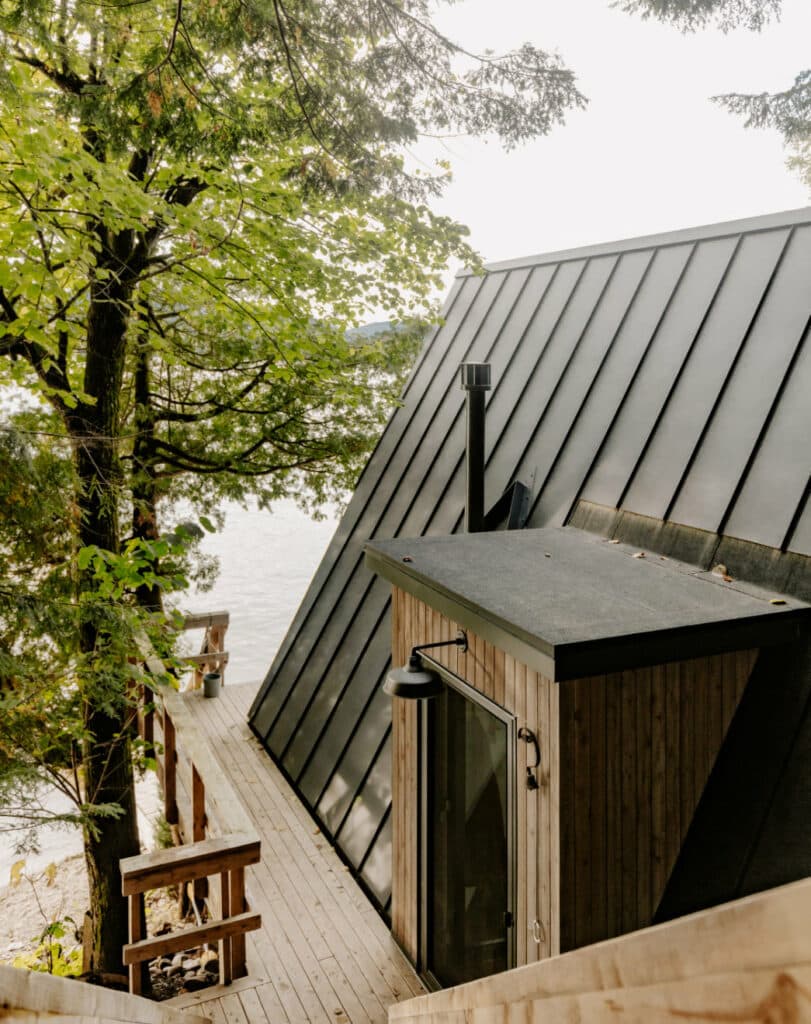 A chalet with a metal roof overlooking a lake.