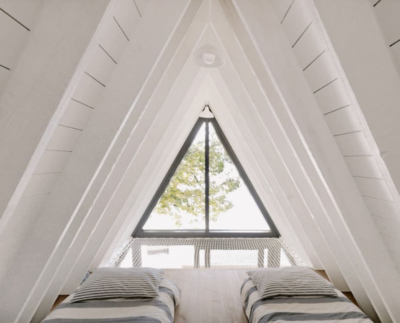 An attic room with two beds and a window in a chalet.