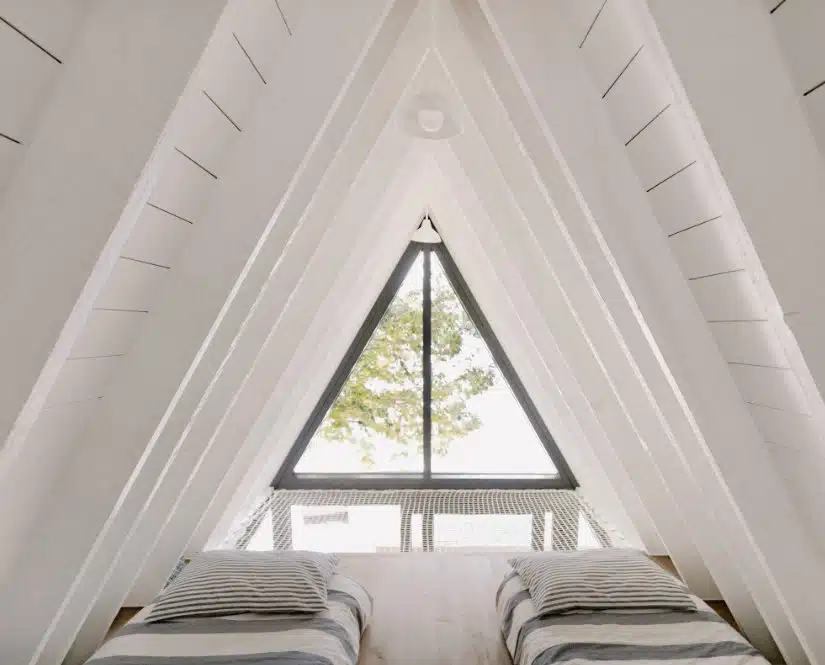 An attic room with two beds and a window in a chalet.