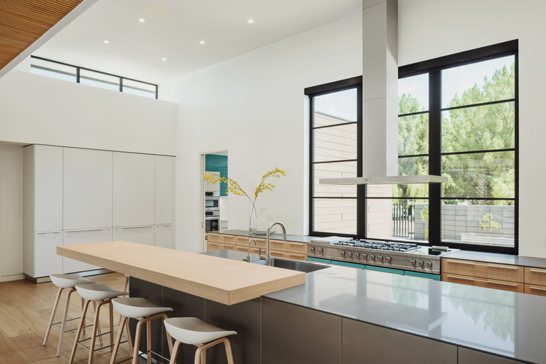 A modern kitchen with wooden floors and a large window.