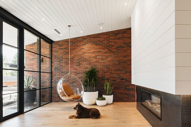 A modern living room with brick walls and a dog laying on the floor.