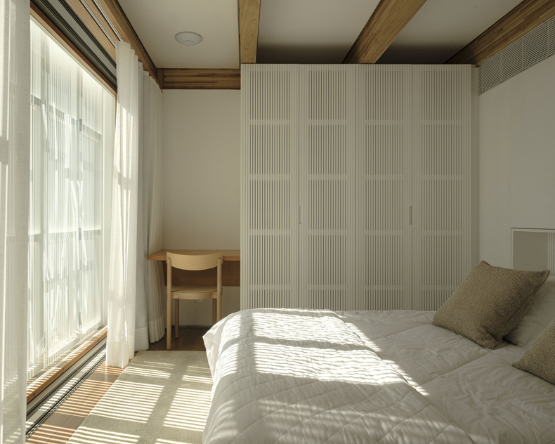 A white bed in a room with a window.
