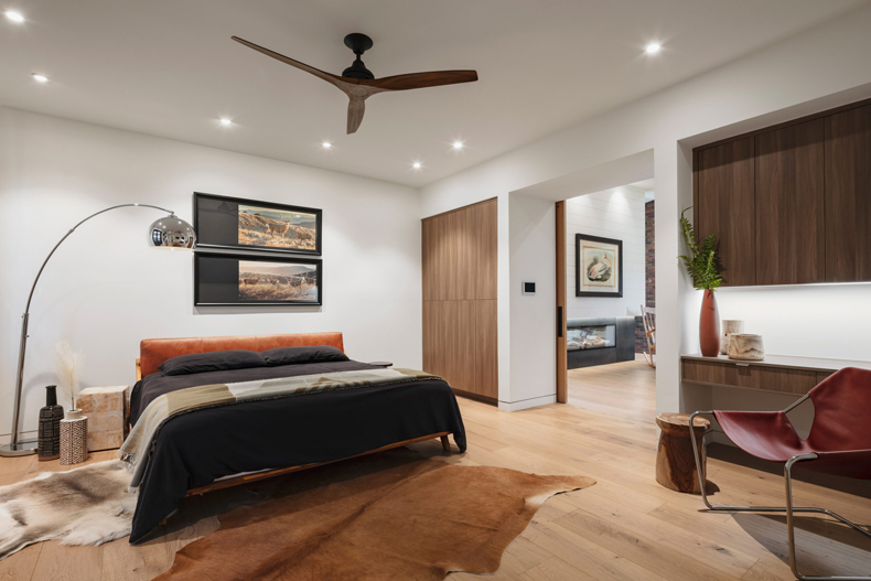 A modern bedroom with wooden floors and a fan.