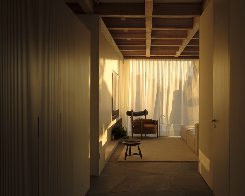 An image of a hallway with a bed and a chair.