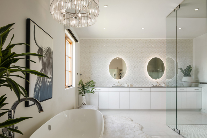 A white bathroom with a large tub and two mirrors.