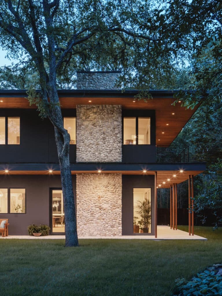 A modern home in the woods at dusk.