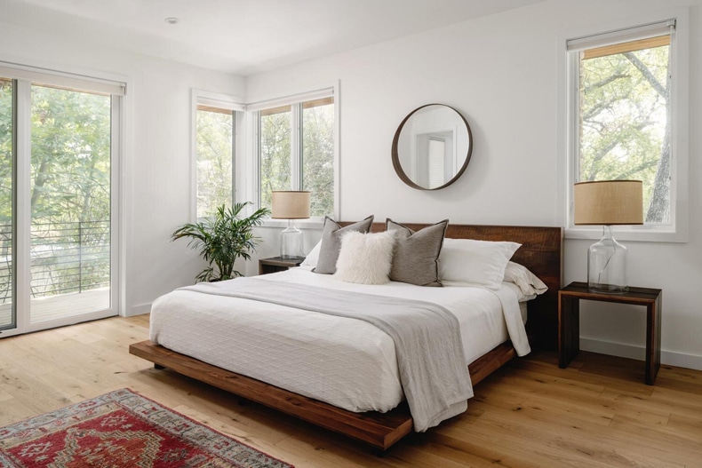 A white bedroom with wood floors and a rug.