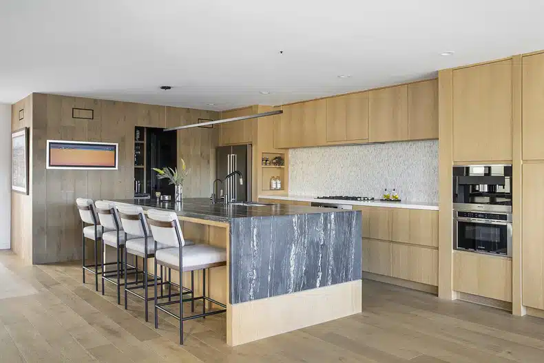 A modern kitchen with wooden cabinets and bar stools.