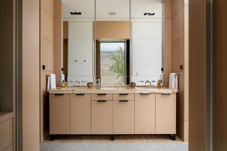 A bathroom with beige cabinets and a mirror.