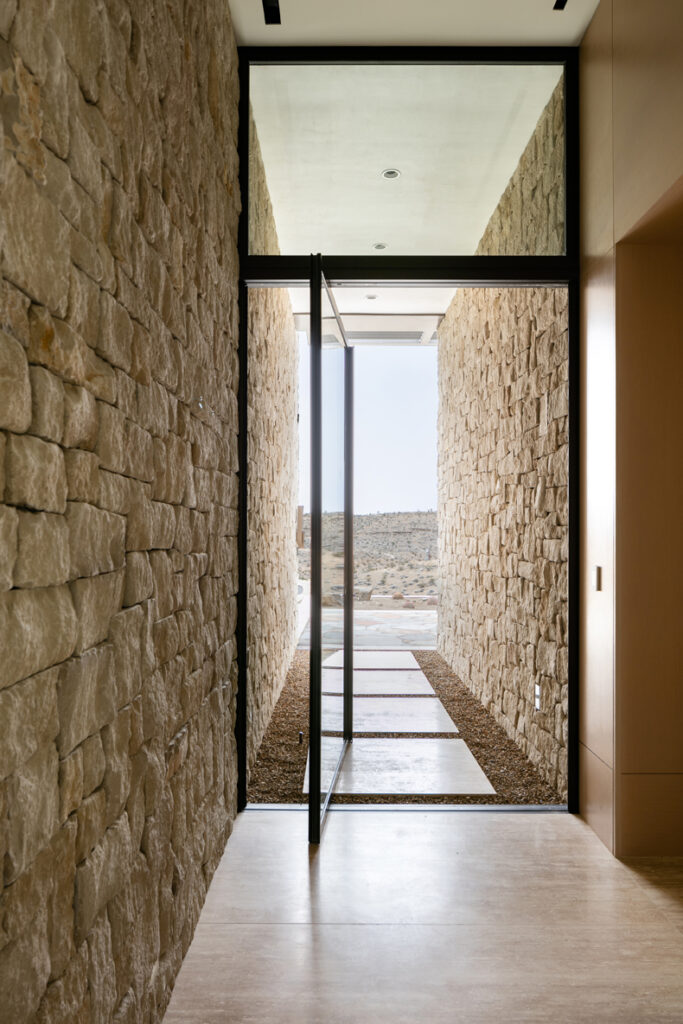 A hallway with a stone wall and glass door.