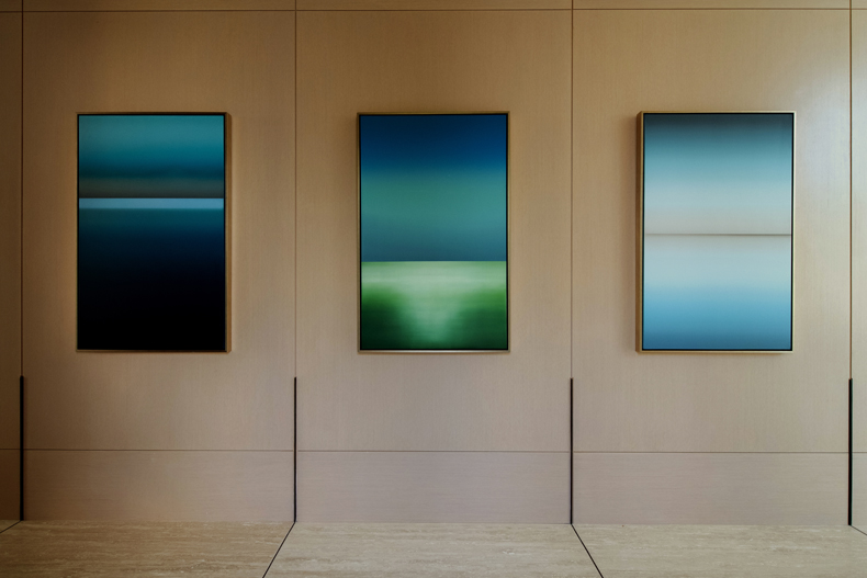 Three paintings hanging on a wall in a room.