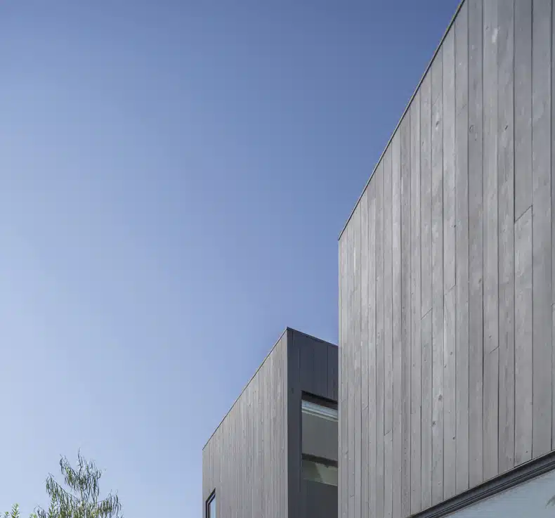 A modern house with wood siding and a blue sky.