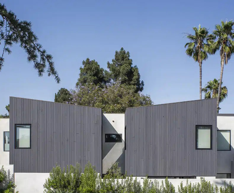 A modern house with a grey exterior and trees.