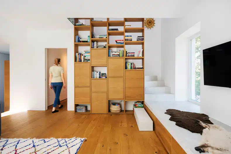 A woman is standing in front of a bookcase in a living room.