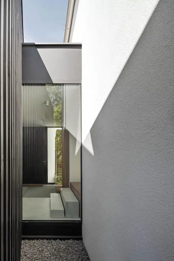 A modern house with black siding and a glass door.