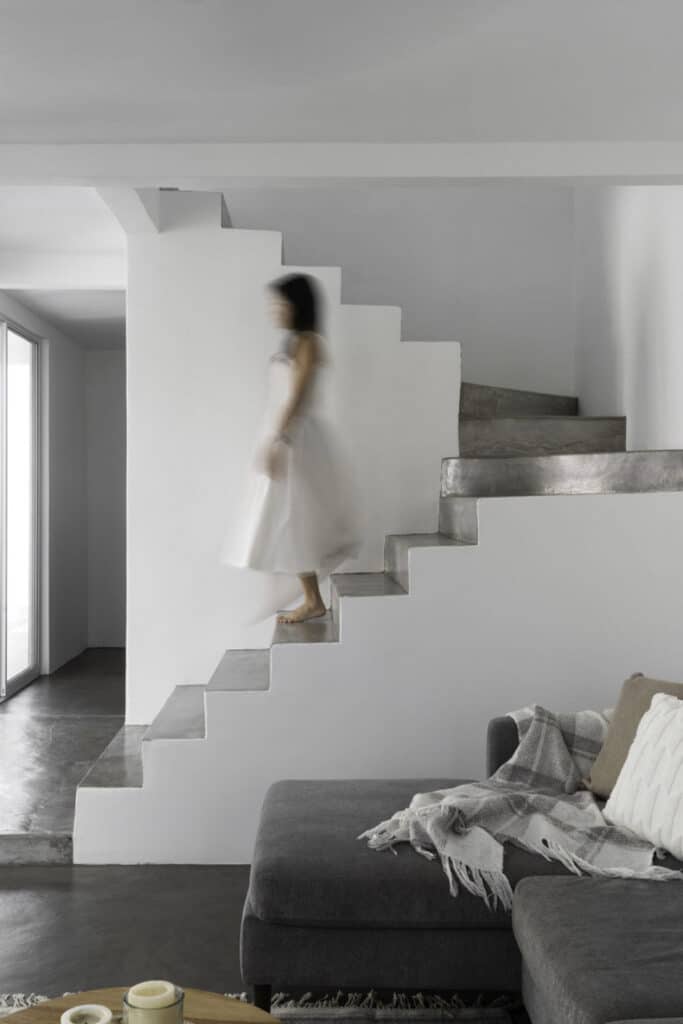 A woman is descending the stairs in a living room.