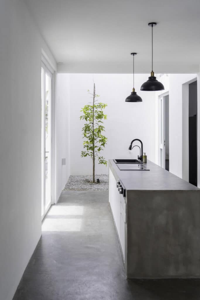 Embark on a Voyage of Discovery: The Splendors of Insight House, featuring a white kitchen with a concrete counter top.
