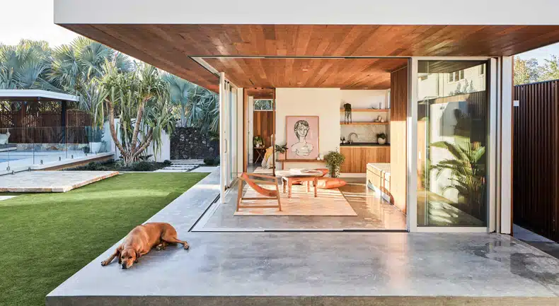 A modern house with a dog laying on the grass.